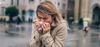 Verkouden vrouw niest in zakdoek