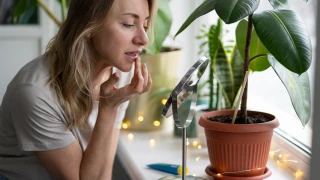 Foto van vrouw met droge lippen die lippenbalsem op lippen smeert voor spiegel