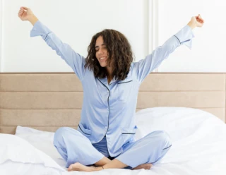 Vrouw zit op bed en rekt zich uit
