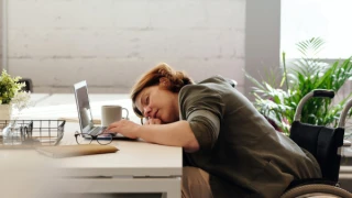 Vrouw ligt met haar hoofd op een open laptop