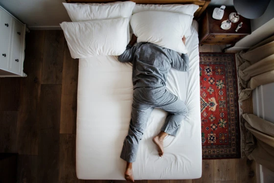 Man op bed en kan niet slapen