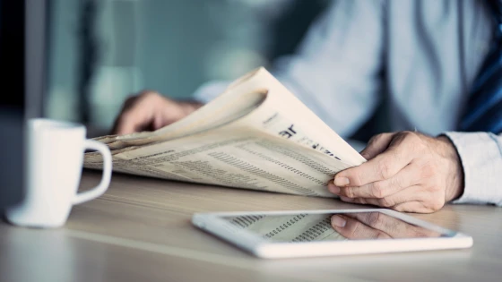 Beeld van een man die het nieuws in de krant leest.