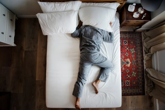 Man op bed en kan niet slapen