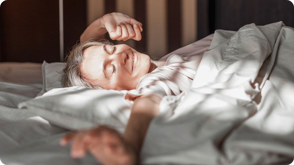 Vrouw van middelbare leeftijd rekt zich uit in bed